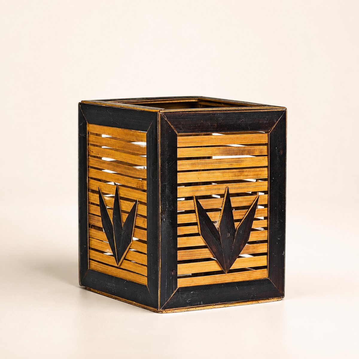 Handcrafted dark and golden bamboo pen stand on a warm off-white studio background