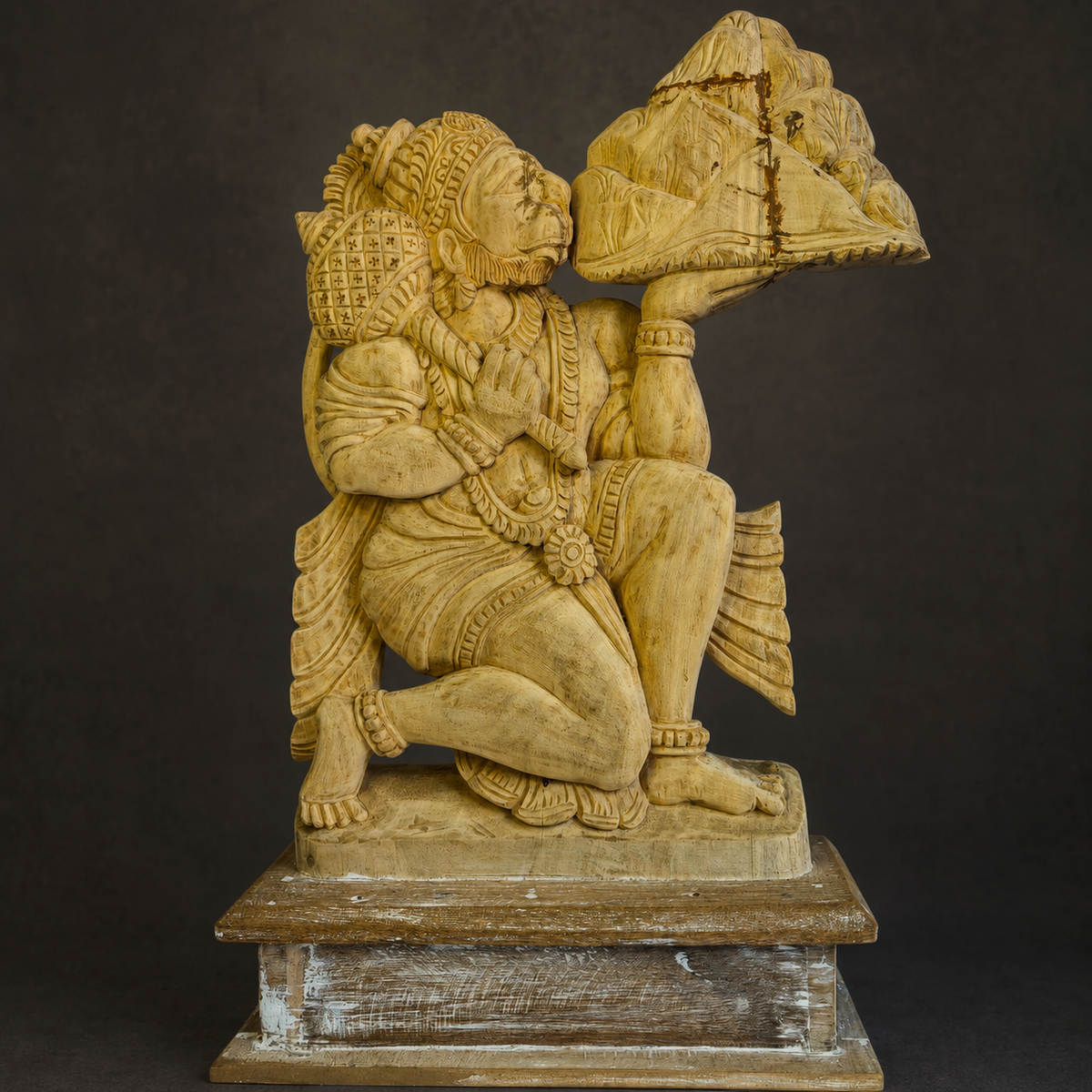 Close view of the crown, jewellery, mountain, wood grain, and carved details on the Bajrangi statue
