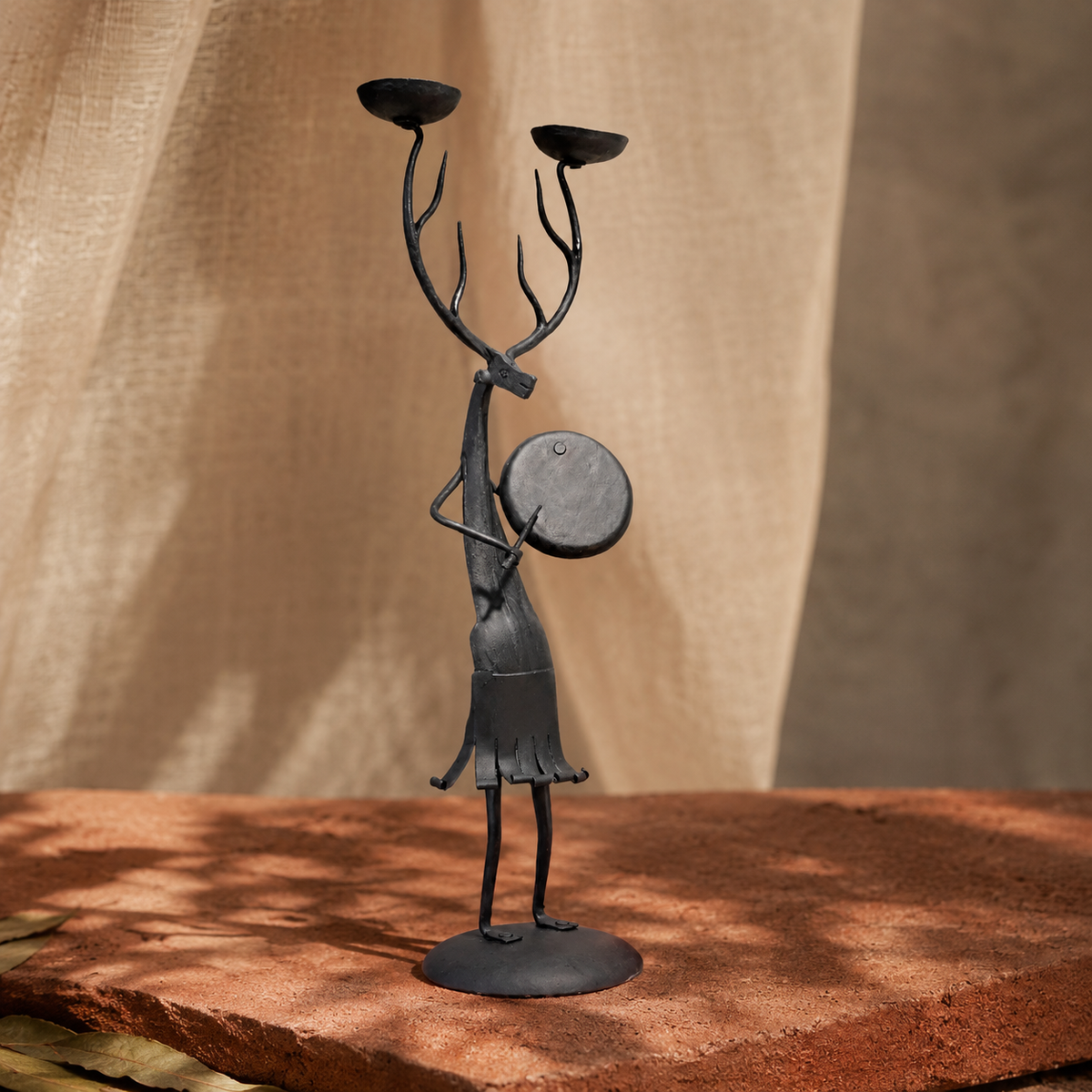 Bastar wrought iron antlered musician candle holder in an earthy editorial setting