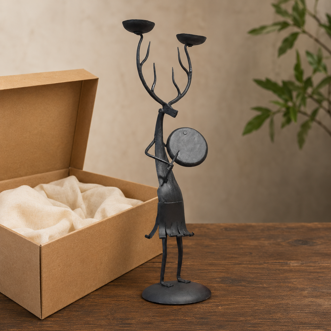 Bastar wrought iron antlered musician candle holder beside an open gift box
