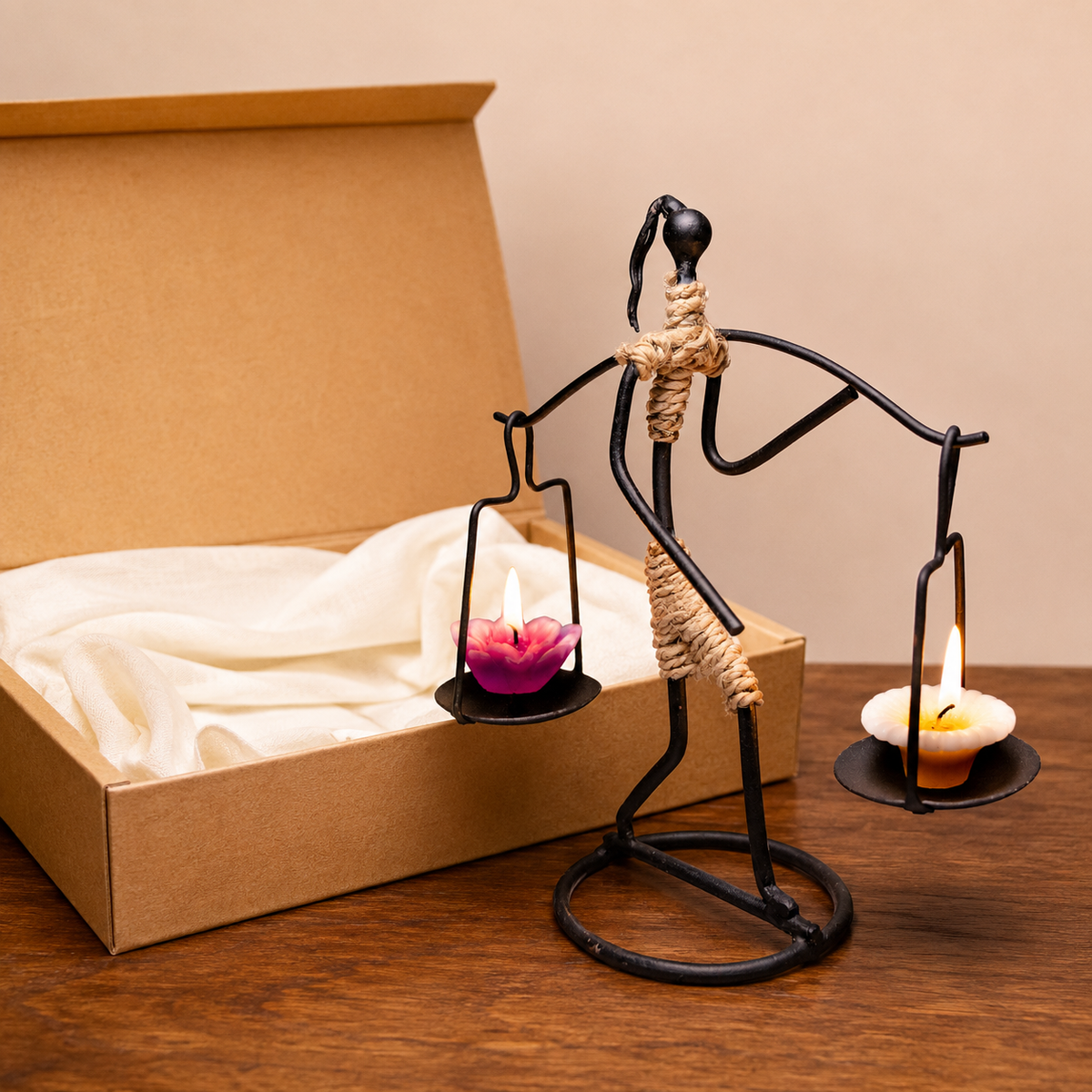 Bastar wrought iron tribal figure candle holder with two lit trays beside a gift box