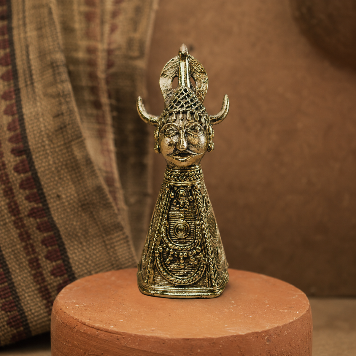 Dhokra Bison Horn Maria brass paperweight displayed on a terracotta pedestal
