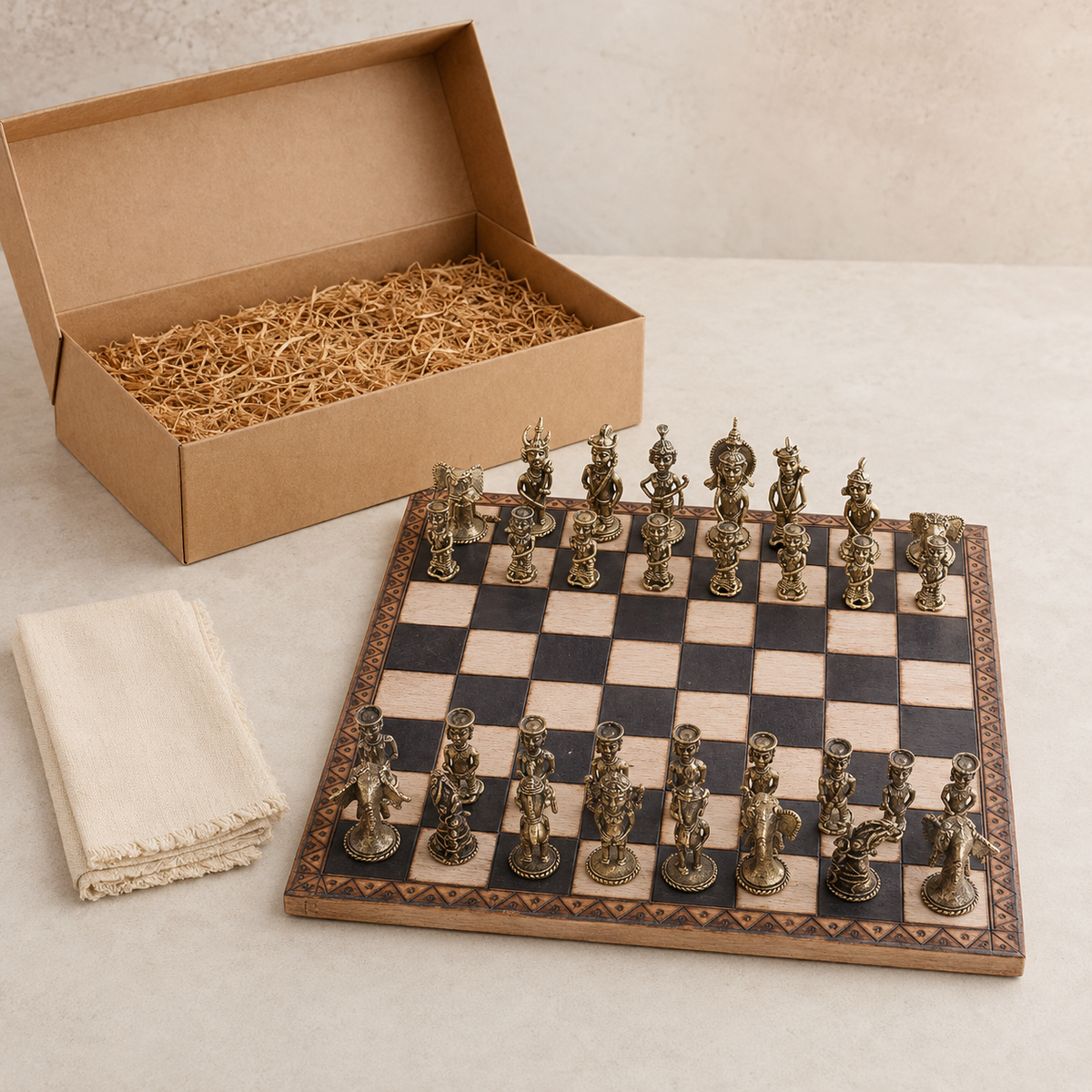 Complete Dhokra brass chess set beside an open kraft presentation box and folded cotton cloth