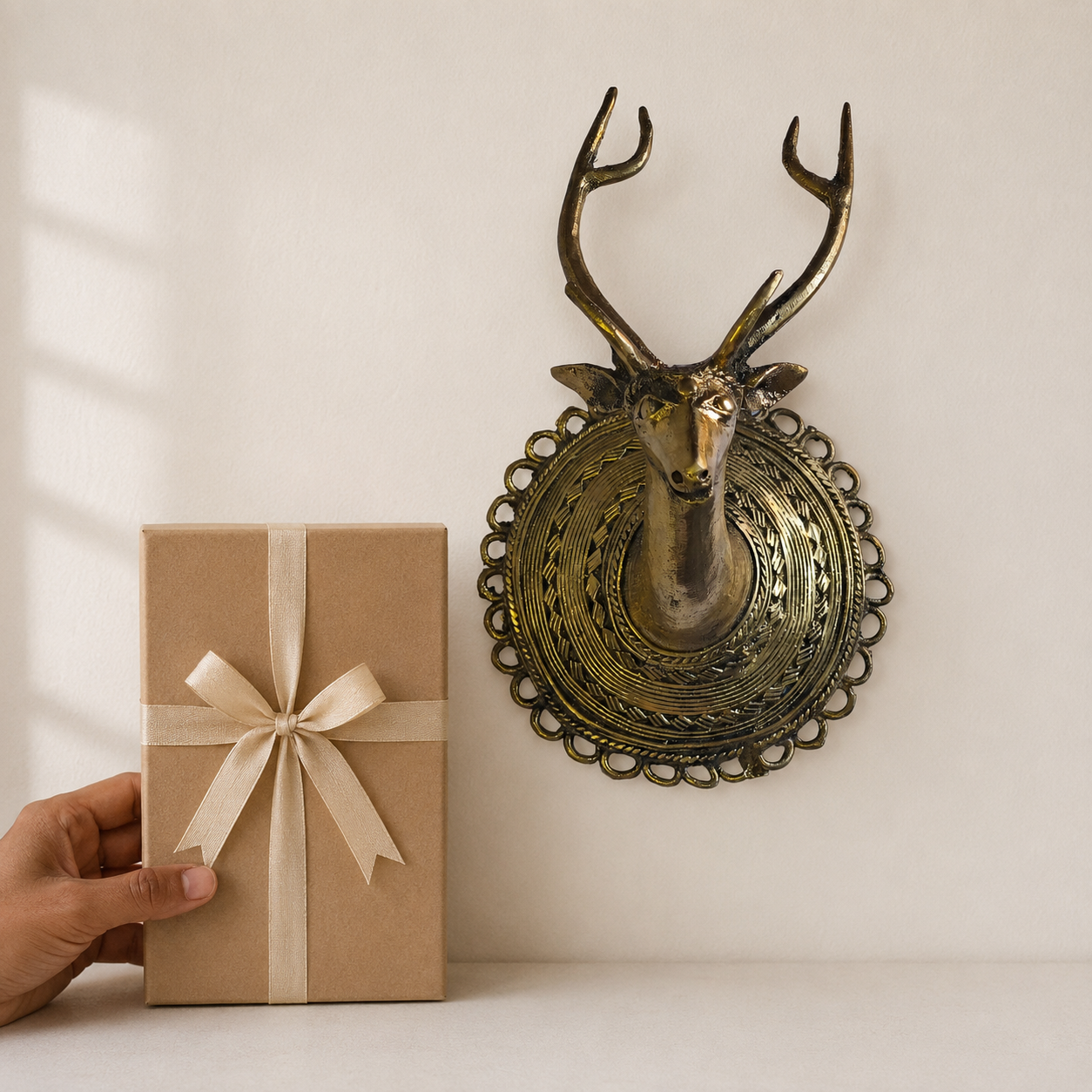 Dhokra Deer Head Design 1 brass wall showpiece beside a ribboned gift box for scale