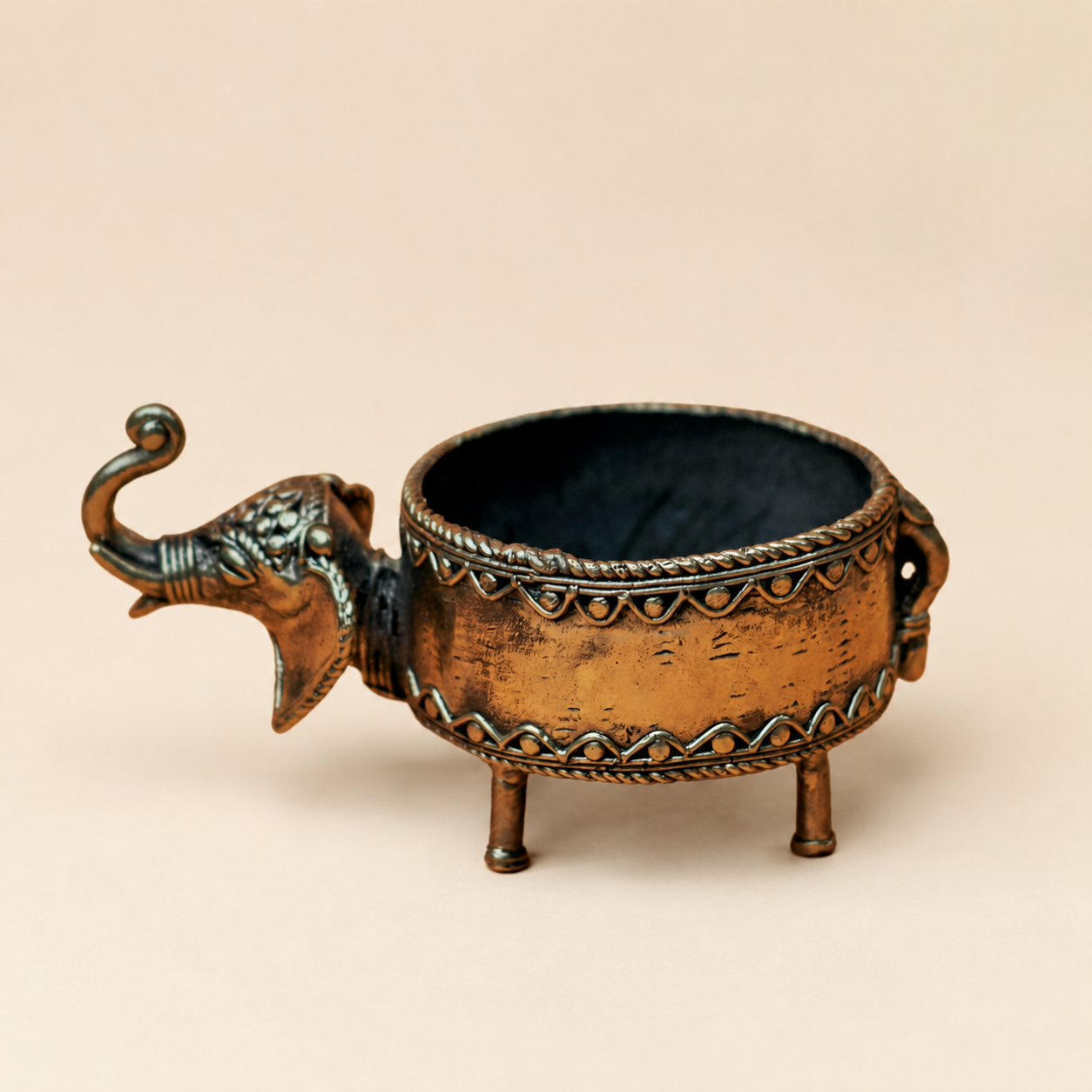 Dhokra elephant dry fruit holder in antique brass on a warm ivory studio background