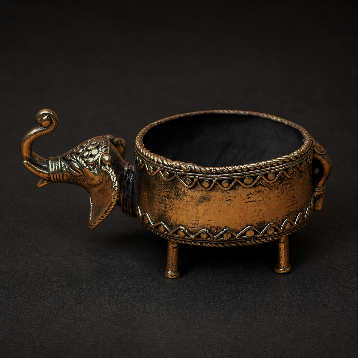 Detailed view of the relief borders and antique brass patina on a Dhokra elephant bowl