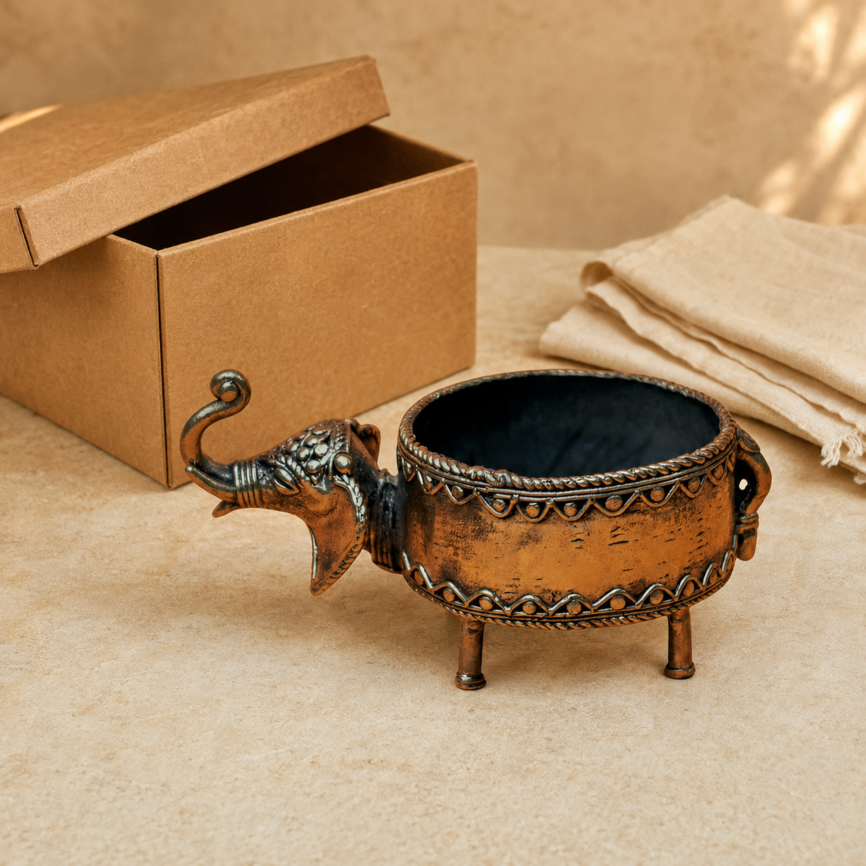 Dhokra elephant dry fruit holder presented beside a kraft gift box and cotton wrap
