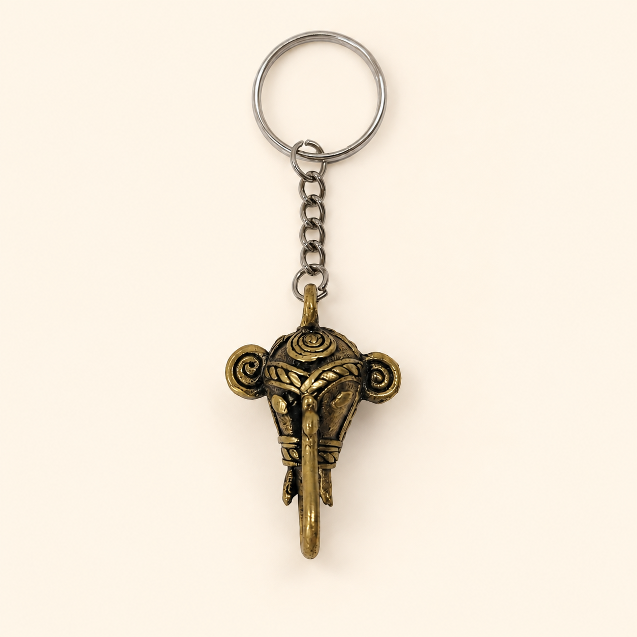 Dhokra elephant keyring with silver ring and antique brass pendant on a warm ivory background