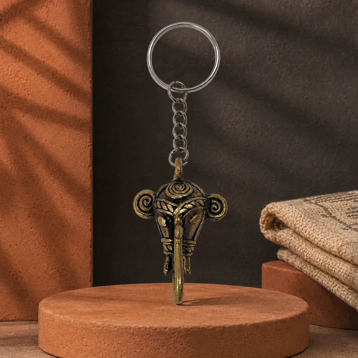 Dhokra elephant keyring displayed on a terracotta plinth in a Bastar-inspired editorial scene