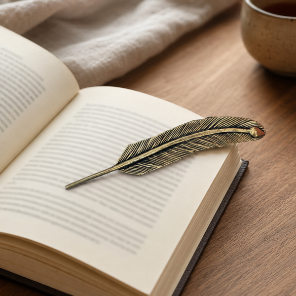 Dhokra brass feather bookmark resting across an open book on a reading table