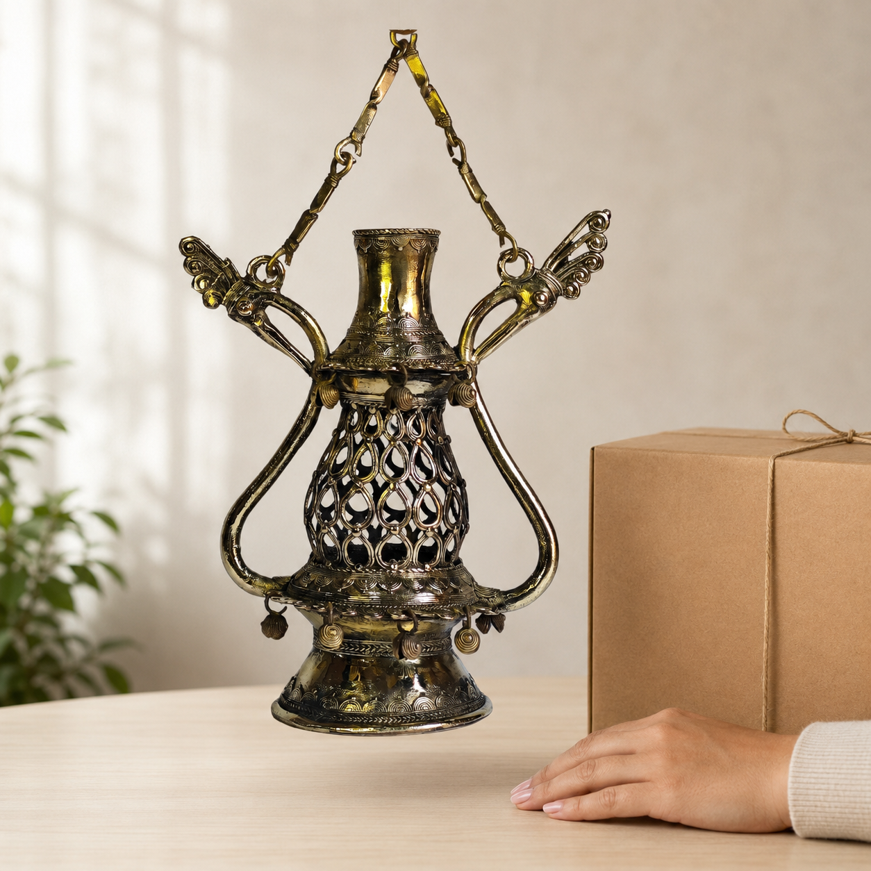 Dhokra Lantern Design 1 brass tribal lamp beside a gift box and hand for scale