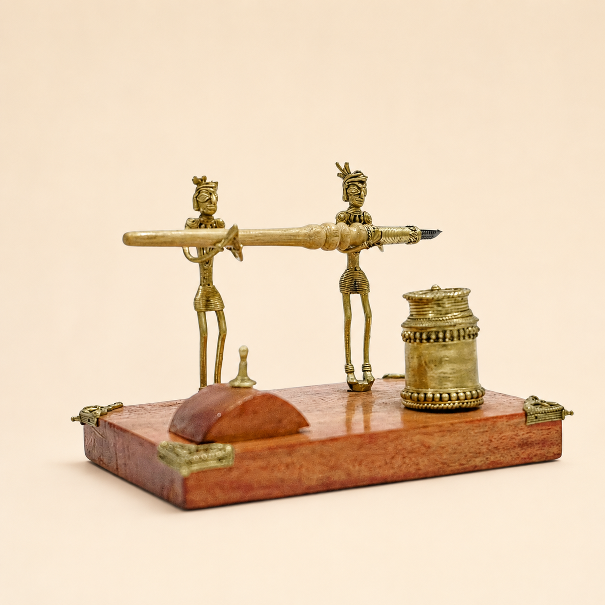 Dhokra pen stand with two tribal figures on a warm ivory studio background