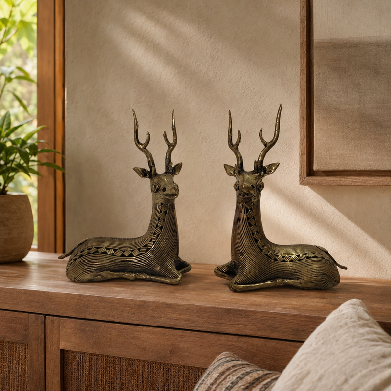 Two reclining Dhokra swamp deer sculptures displayed on a wooden console in a warm living room
