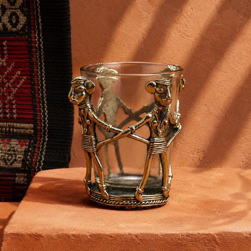 Dhokra brass tea holder displayed on a terracotta plinth in a Bastar craft setting