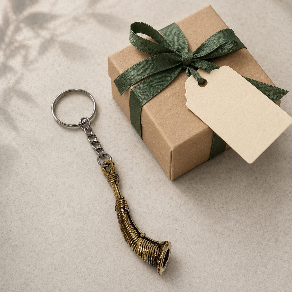 Dhokra Todi brass keyring with silver split ring, short chain and curved ribbed pendant beside a ribboned gift box