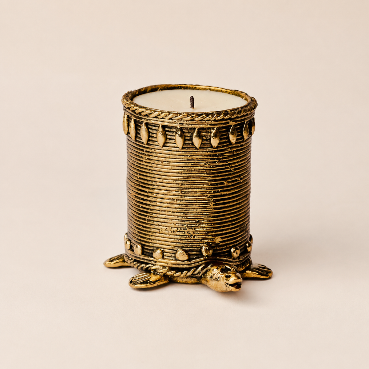 Dhokra tortoise candle holder with antique brass wire texture on an ivory studio background