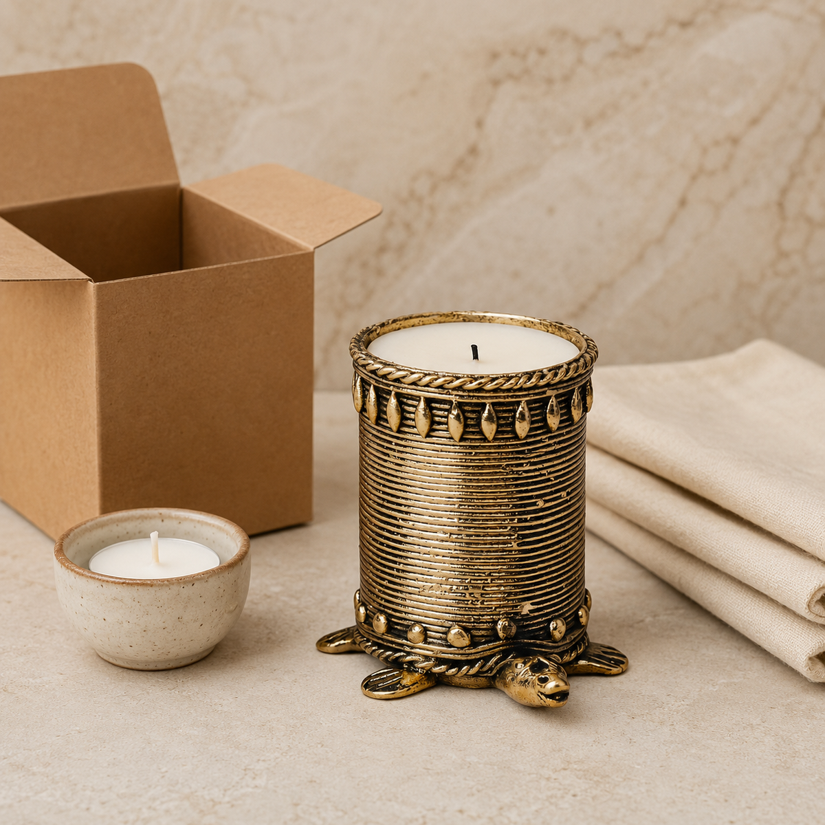 Dhokra tortoise candle holder beside a kraft gift box and candle accessories