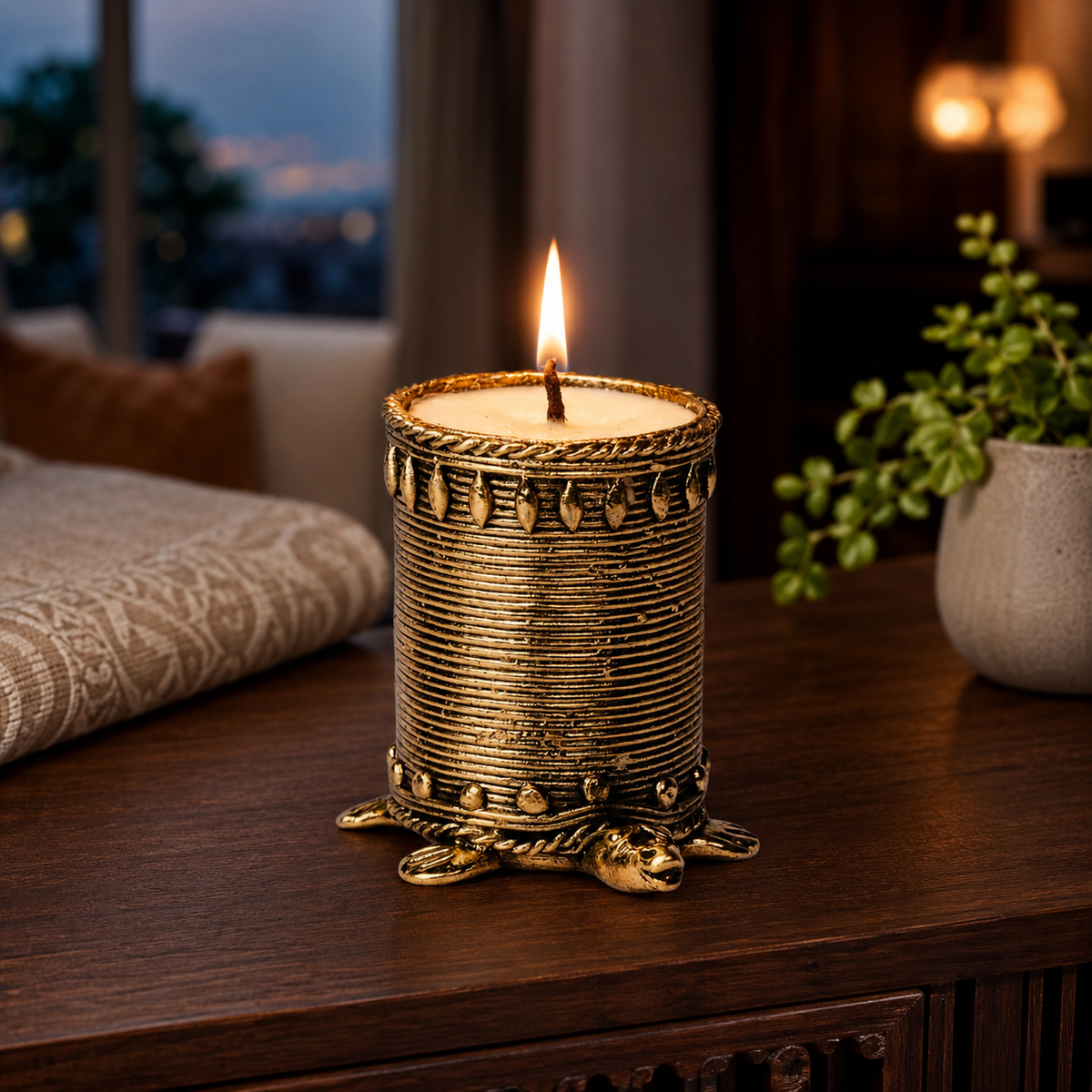 Lit Dhokra tortoise candle holder on a wooden console in a warm evening interior