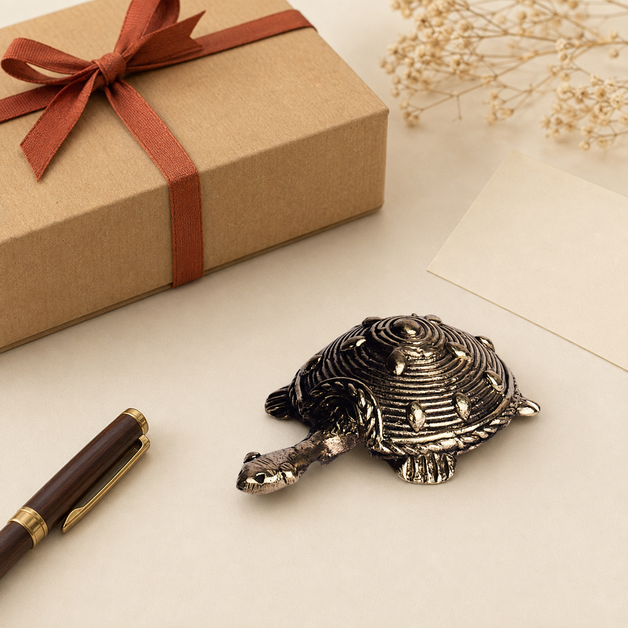 Dhokra tortoise paperweight presented beside a kraft gift box and pen