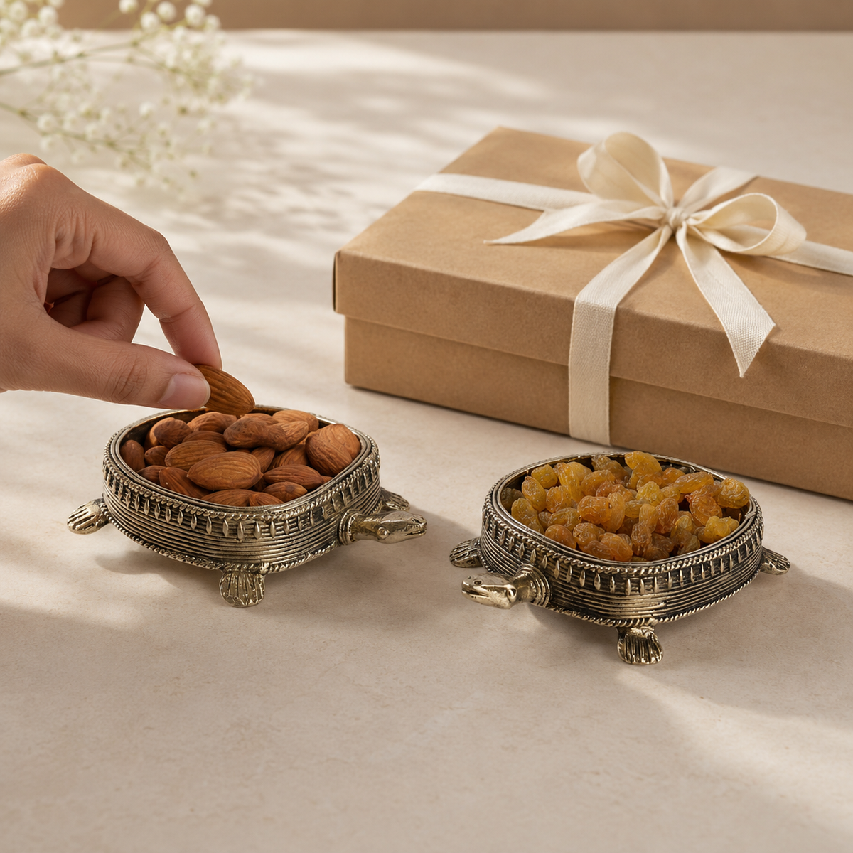 Pair of Dhokra tortoise dry fruit holders with almonds and raisins beside a ribboned gift box