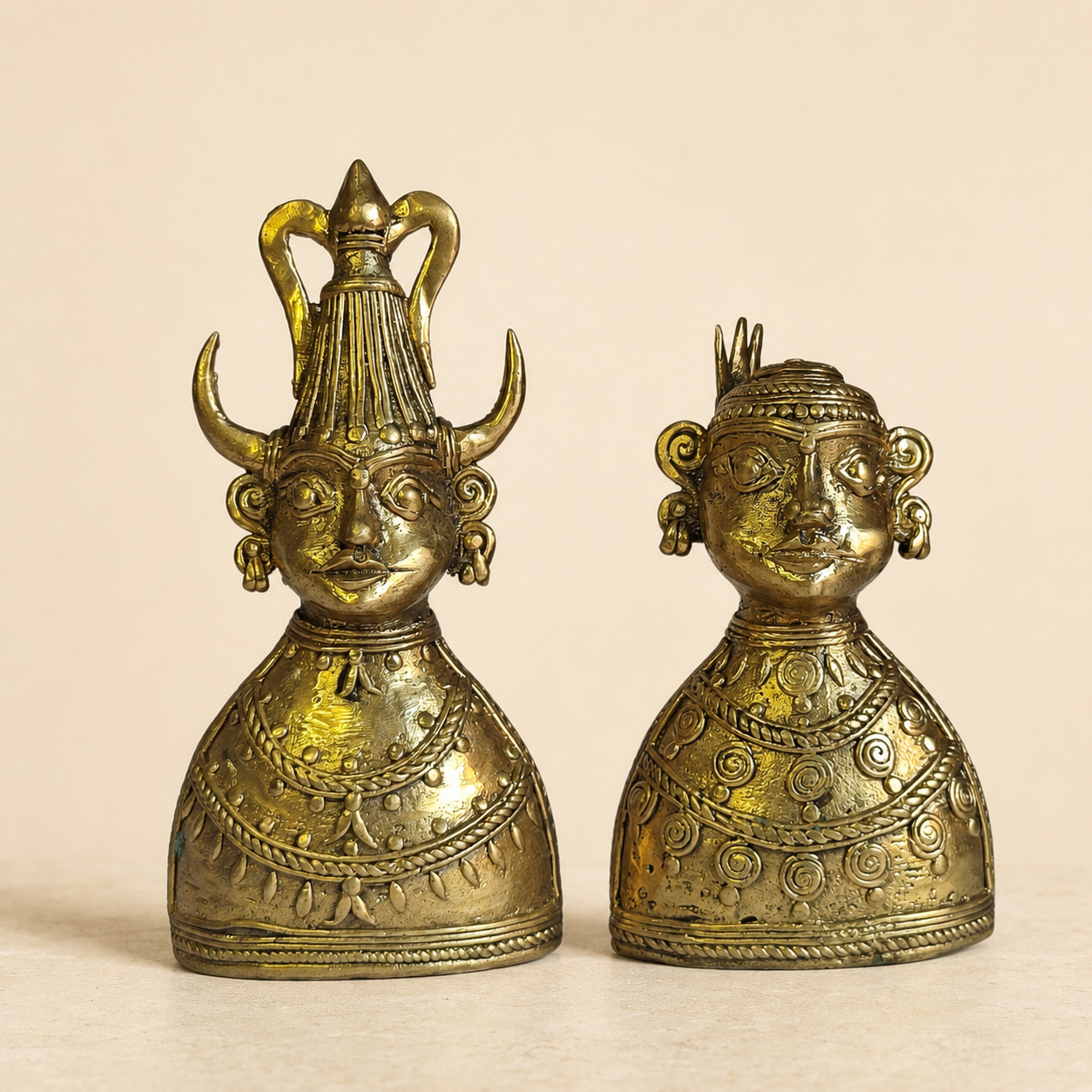 Set of two handcrafted Dhokra tribal bust figurines photographed on a warm ivory studio background