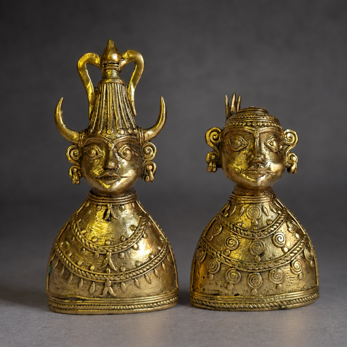 Craft detail of the headdresses, spiral reliefs and hand-cast brass texture on two Dhokra bust figurines