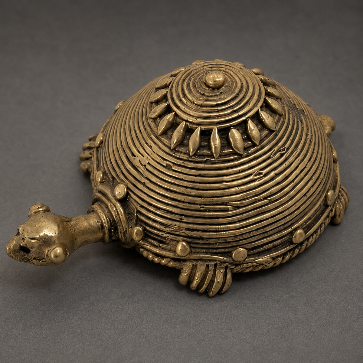 Close detail of the concentric shell coils and floral crest on a handcrafted Dhokra turtle