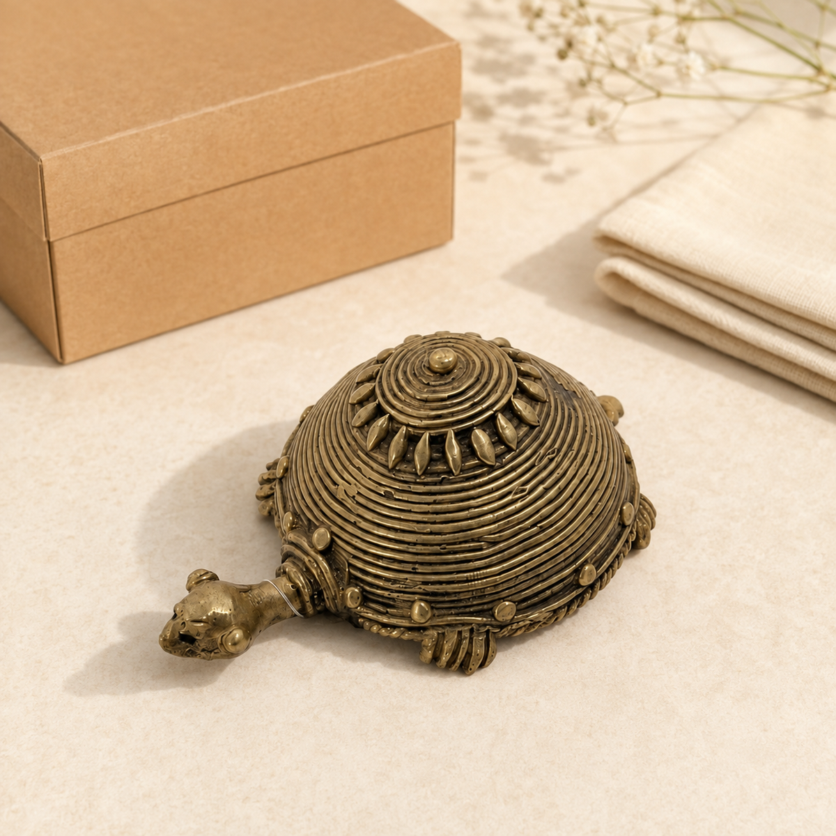 Handcrafted Dhokra brass turtle presented beside a kraft gift box and folded cotton cloth