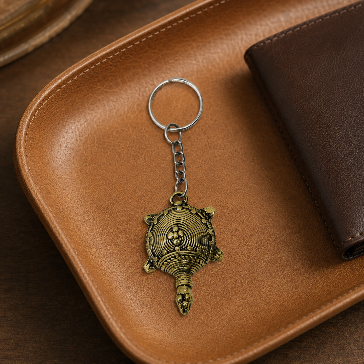 Dhokra turtle keyring on a tan leather valet tray beside a wallet