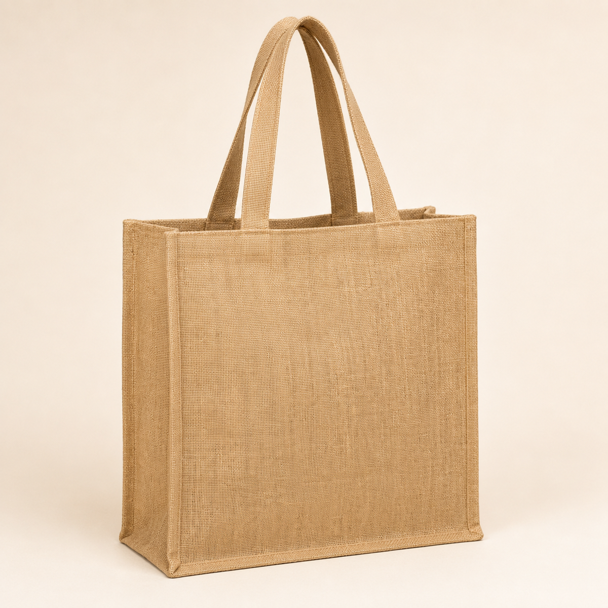 Plain natural jute tote bag with broad handles on a warm ivory catalogue background