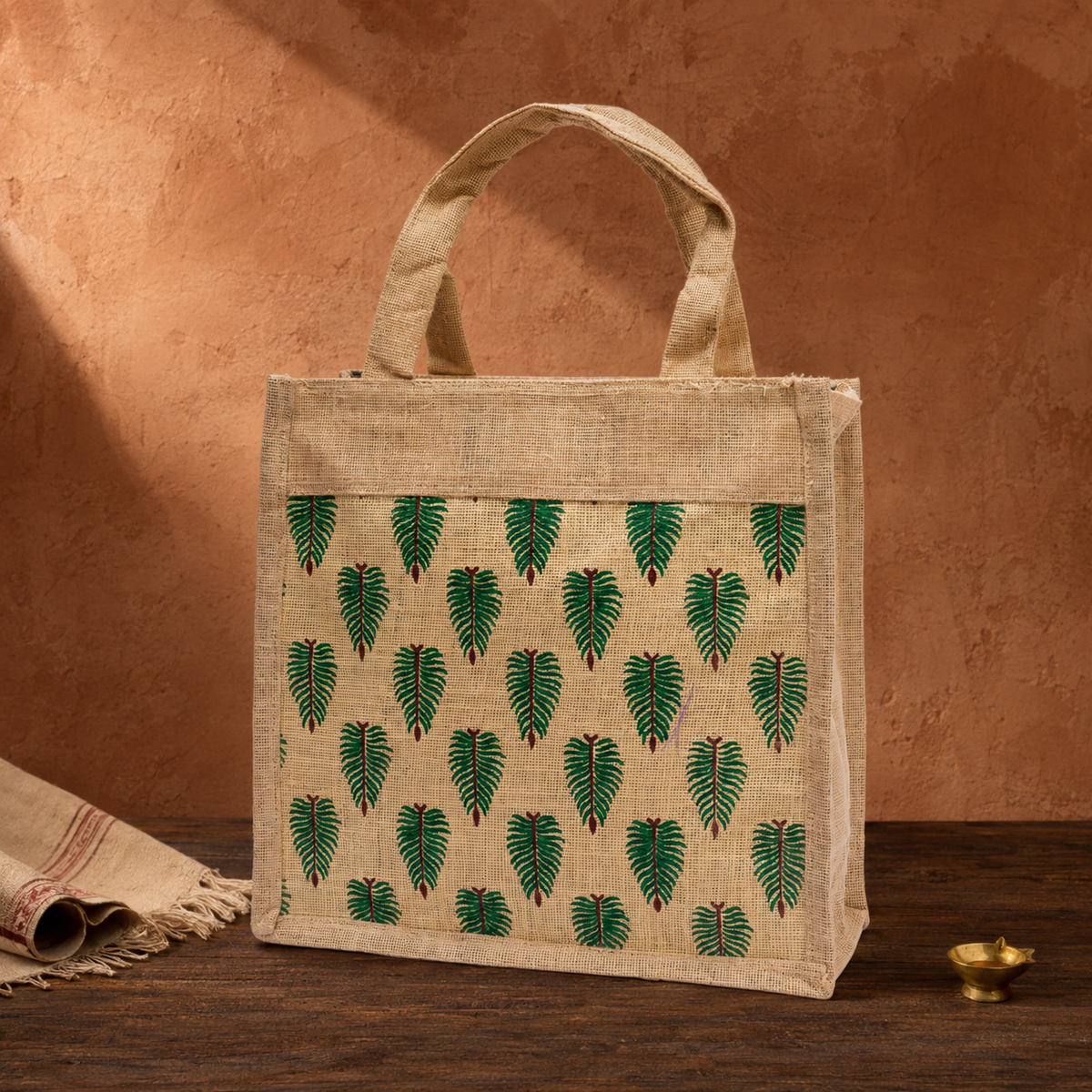 Bastar handcrafted jute tote with green leaf motifs in a terracotta editorial setting