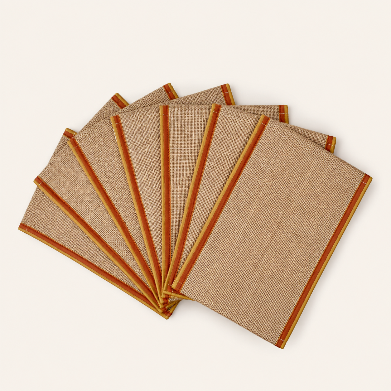 Six handcrafted natural jute notepads arranged in a fan on a warm ivory background