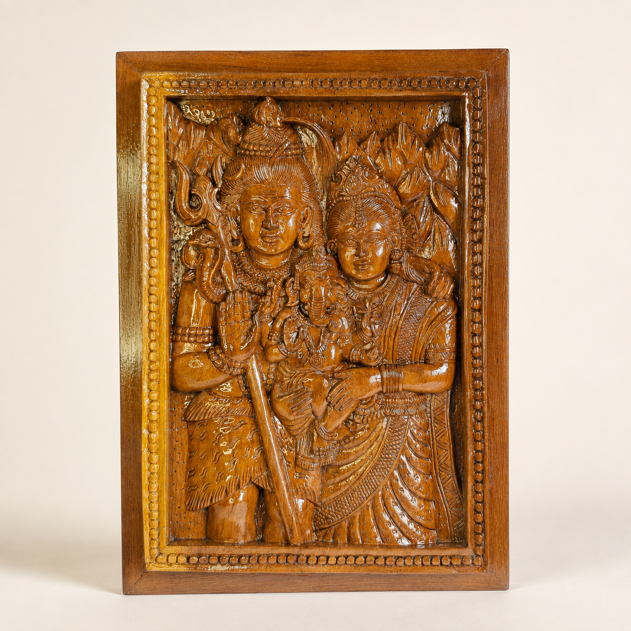 Hand-carved Shankar, Parvati and Ganesh wooden relief panel on a clean studio background