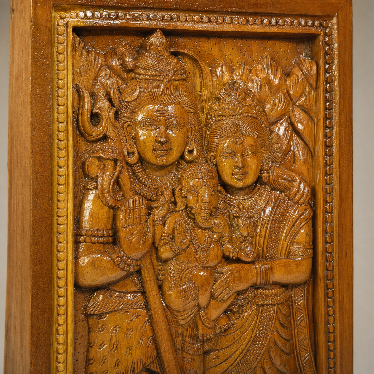 Close view of the carved faces, jewellery and wood grain on the Shankar-Parvati relief