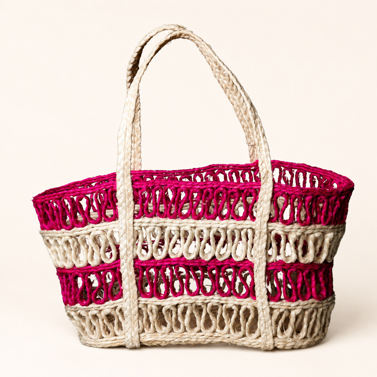 Handcrafted cream and magenta sisal tote bag on a clean warm studio background