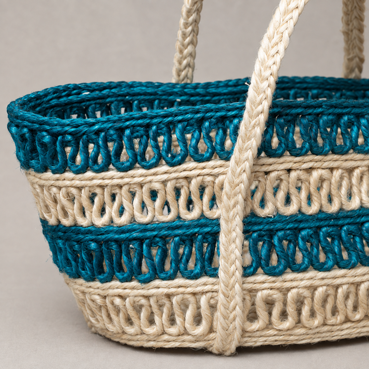 Close detail of teal and natural cream open-loop sisal weaving and braided handles
