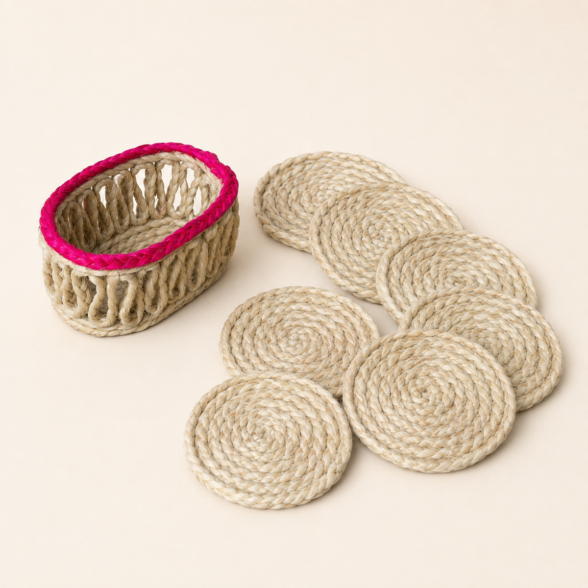 Six handcrafted sisal coasters with a magenta-rimmed woven holder on an ivory background