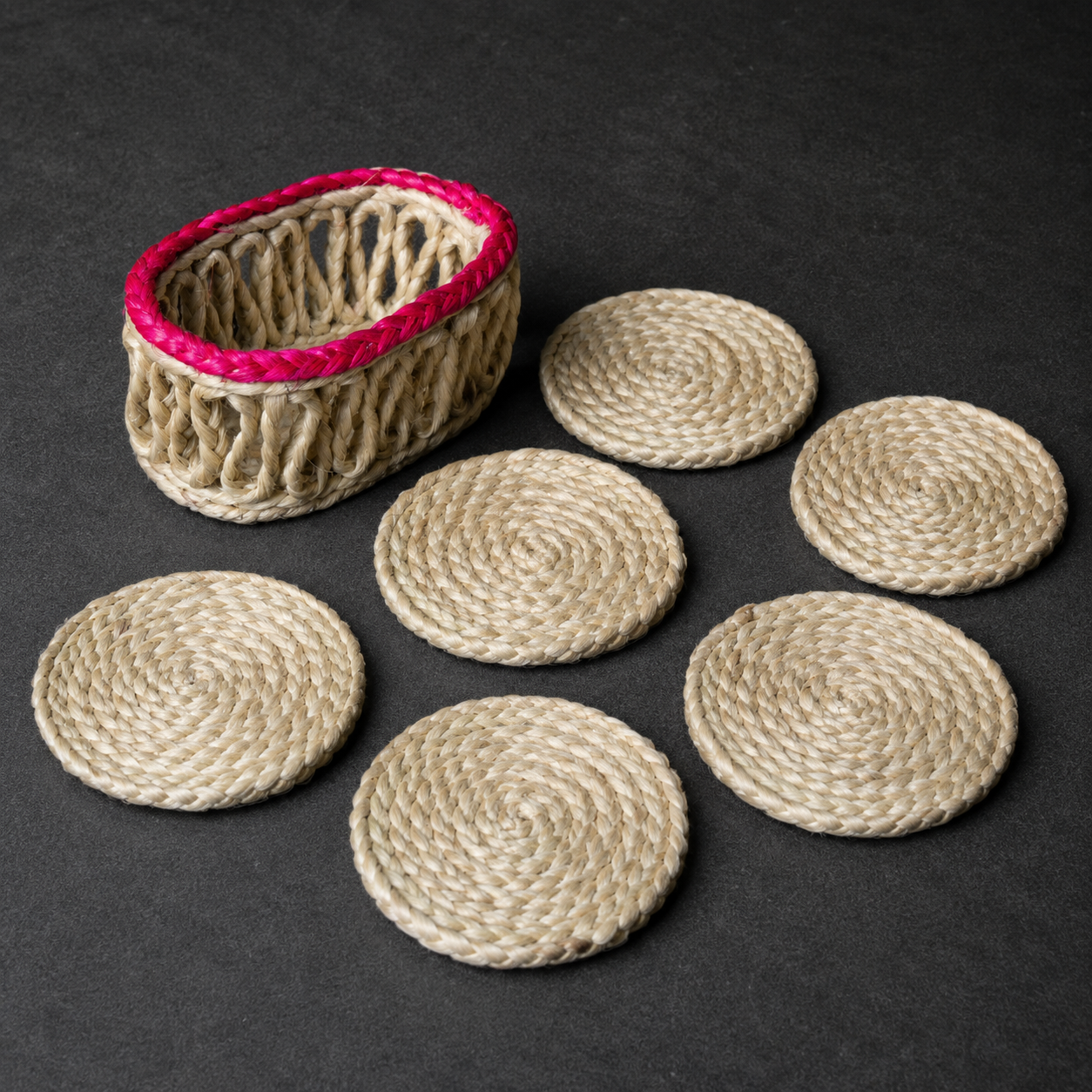 Detailed view of six spiral-braided sisal coasters and their open-weave holder