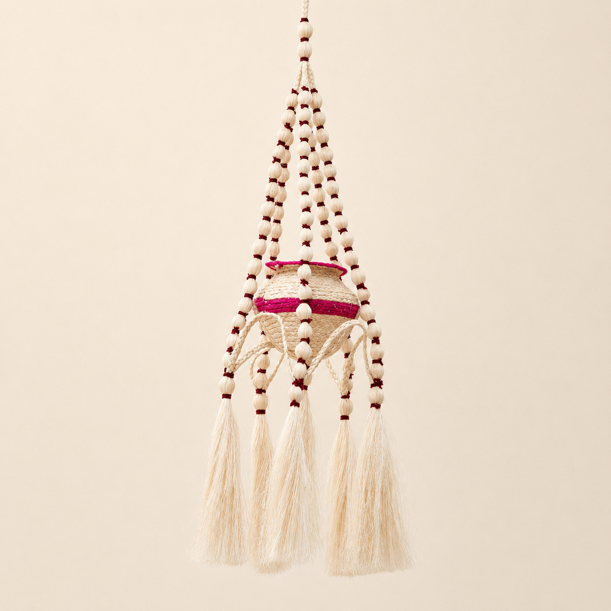 Natural sisal hanging planter with magenta accents on a warm ivory background
