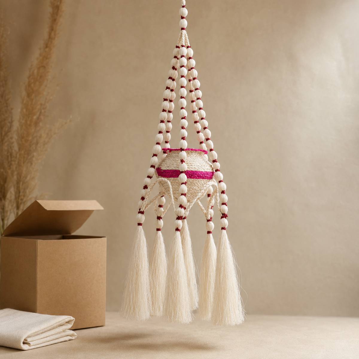 Handcrafted sisal hanging planter presented beside a kraft gift box and cotton wrap