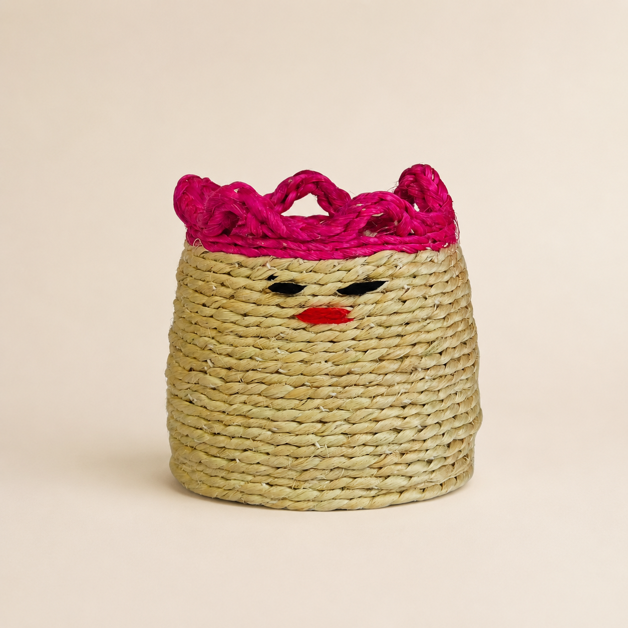Sisal pen stand with natural coiled fibre and magenta braided rim on an ivory studio background