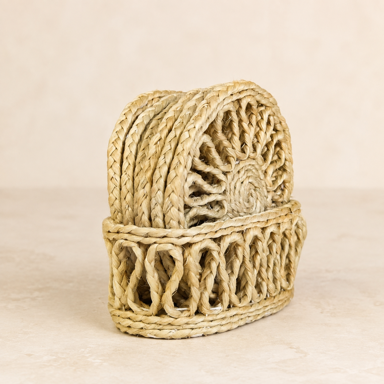 Natural sisal table coaster set in its woven holder on a clean warm ivory studio background