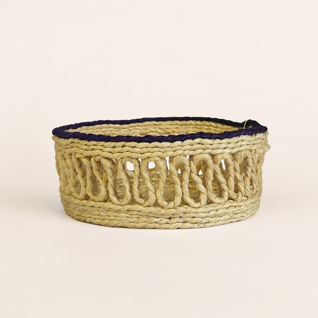 Handcrafted pale-golden sisal table container with dark purple rim on a clean studio background