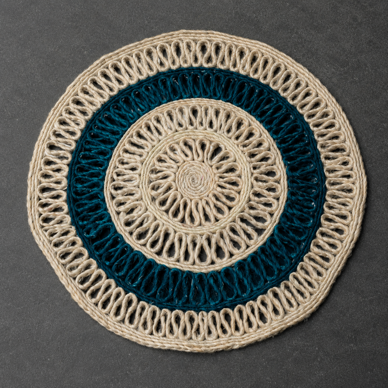 Detailed view of the concentric open-loop weave and braided rim of a sisal table mat