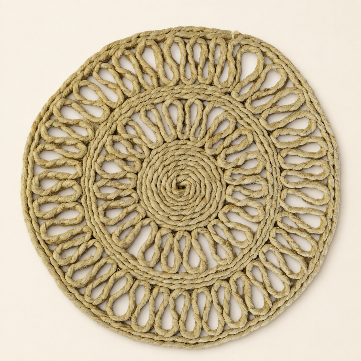 Natural sisal table mat with spiral centre and open-loop weave on a warm ivory background