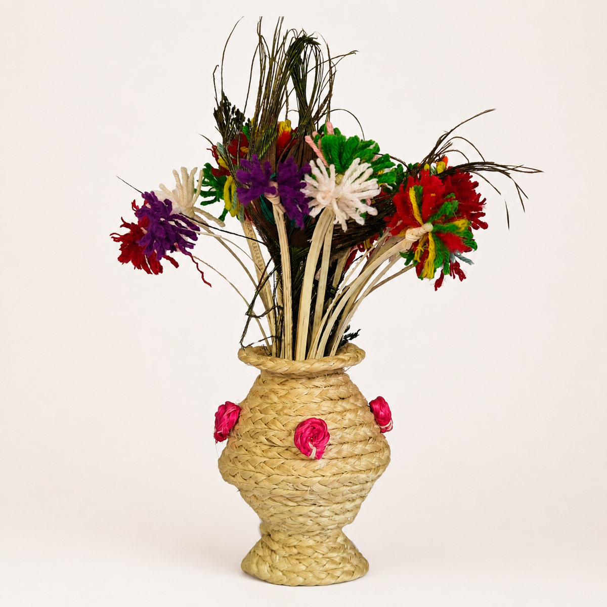Handcrafted pale-golden sisal table vase with multicolour fibre flowers on a warm white background