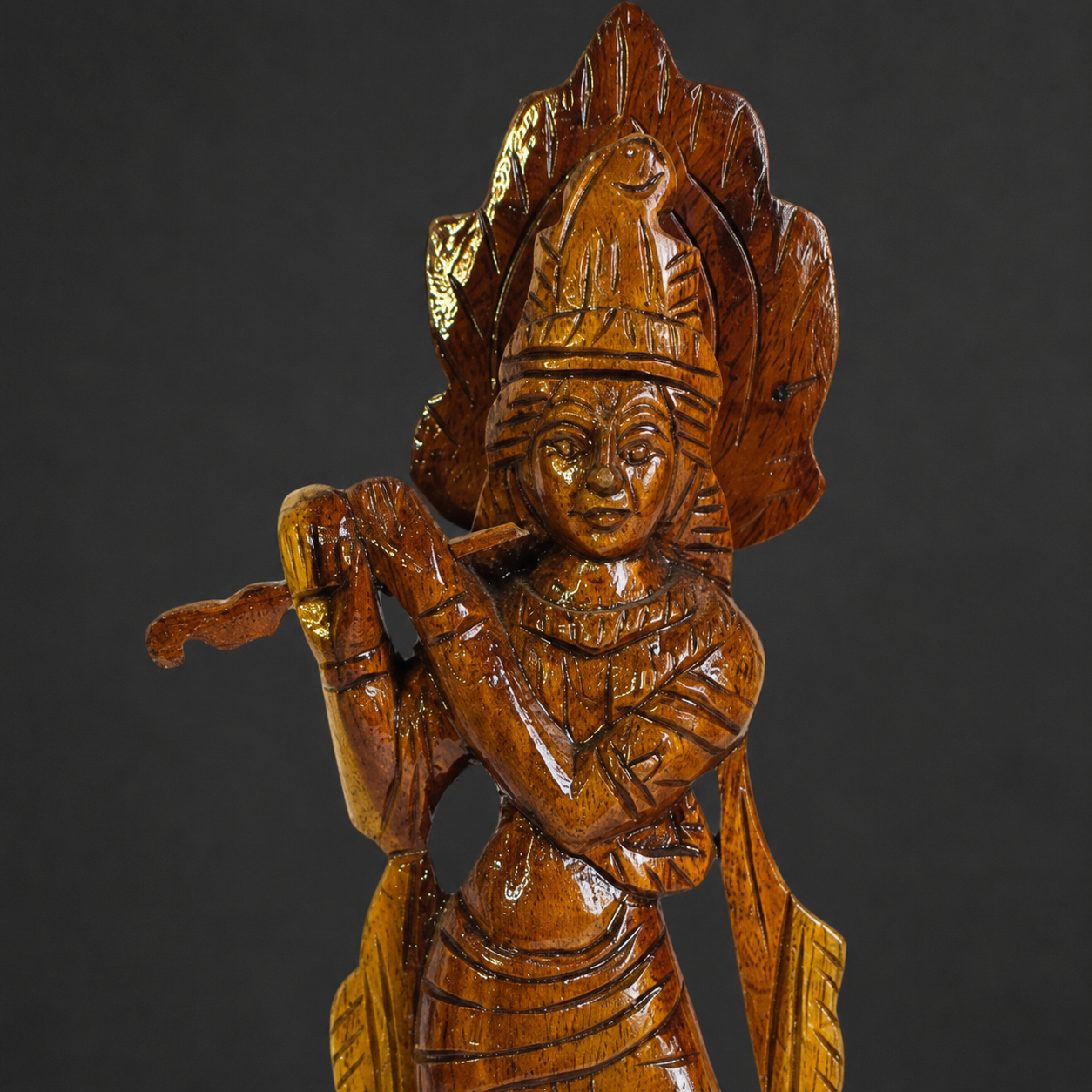 Close craftsmanship detail of Krishna's crown, face, flute, hands and carved wood grain