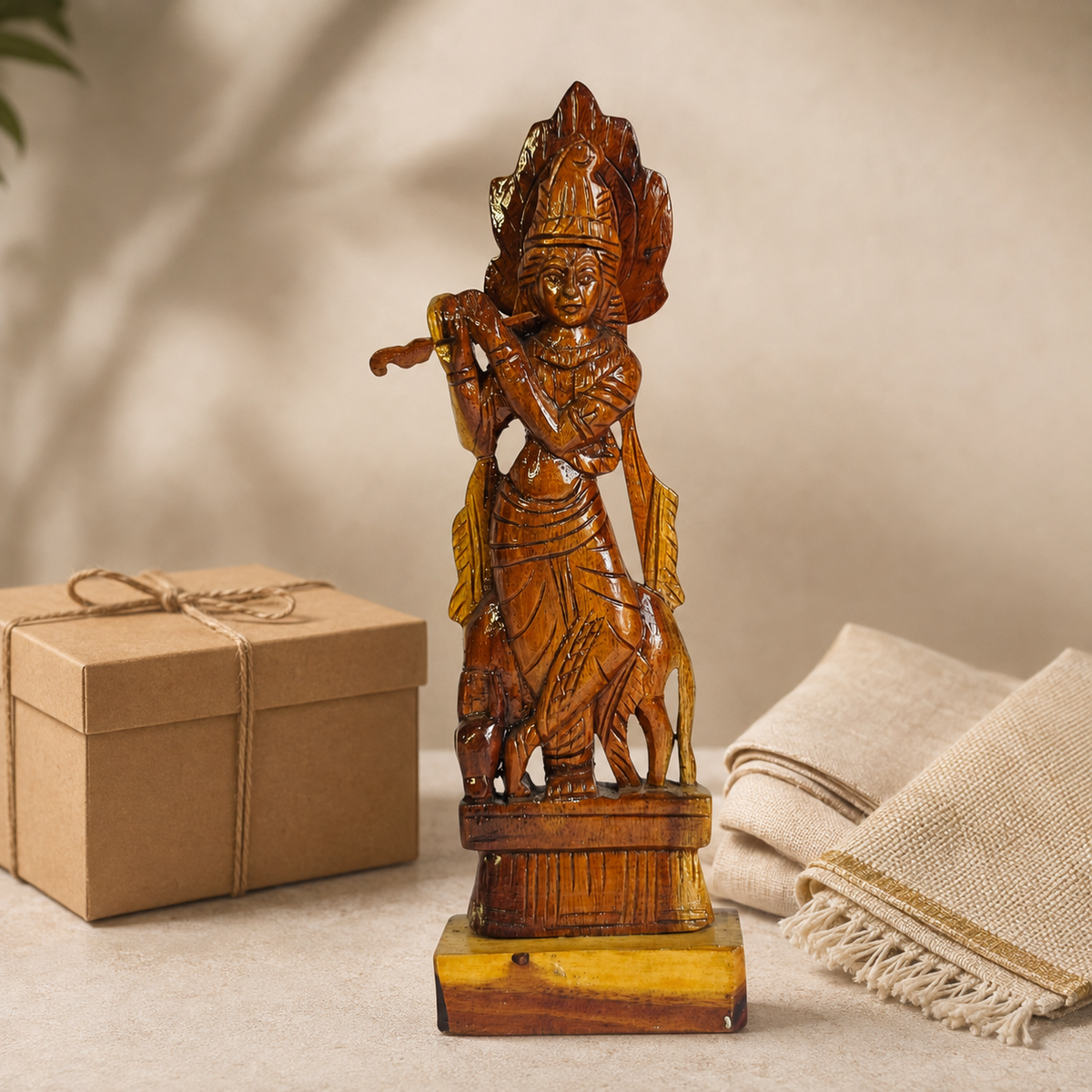 Bastar wooden Krishna statue arranged beside a kraft gift box and folded handloom cloth