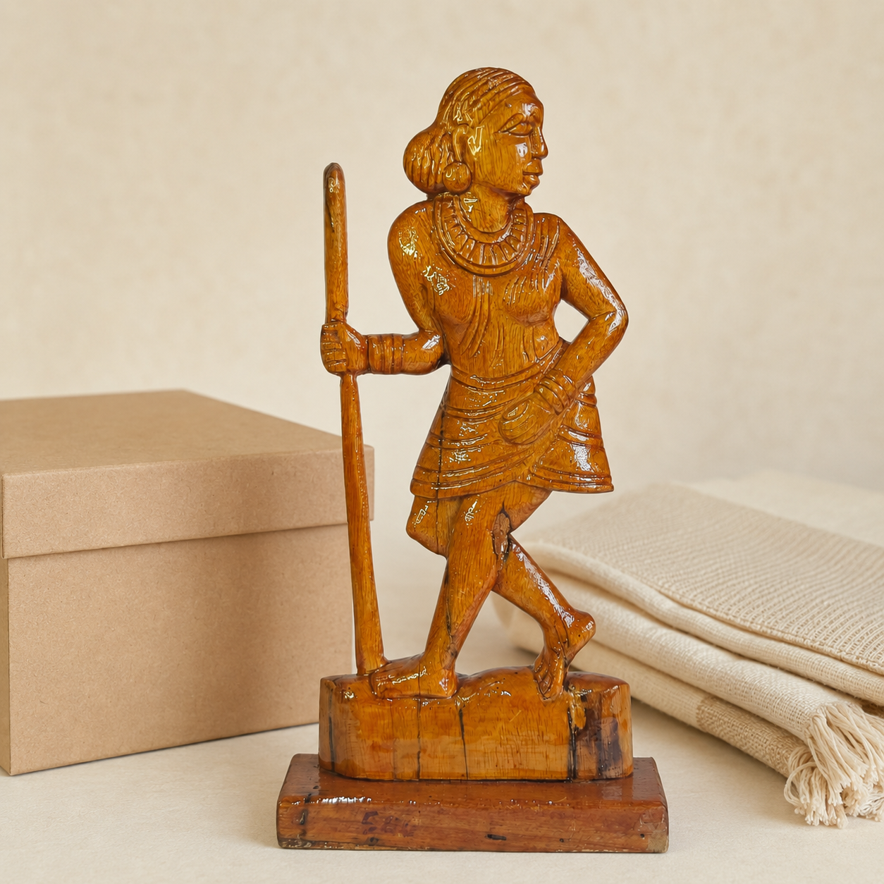 Bastar wooden Madin woman sculpture presented beside a kraft gift box and cream handloom cloth