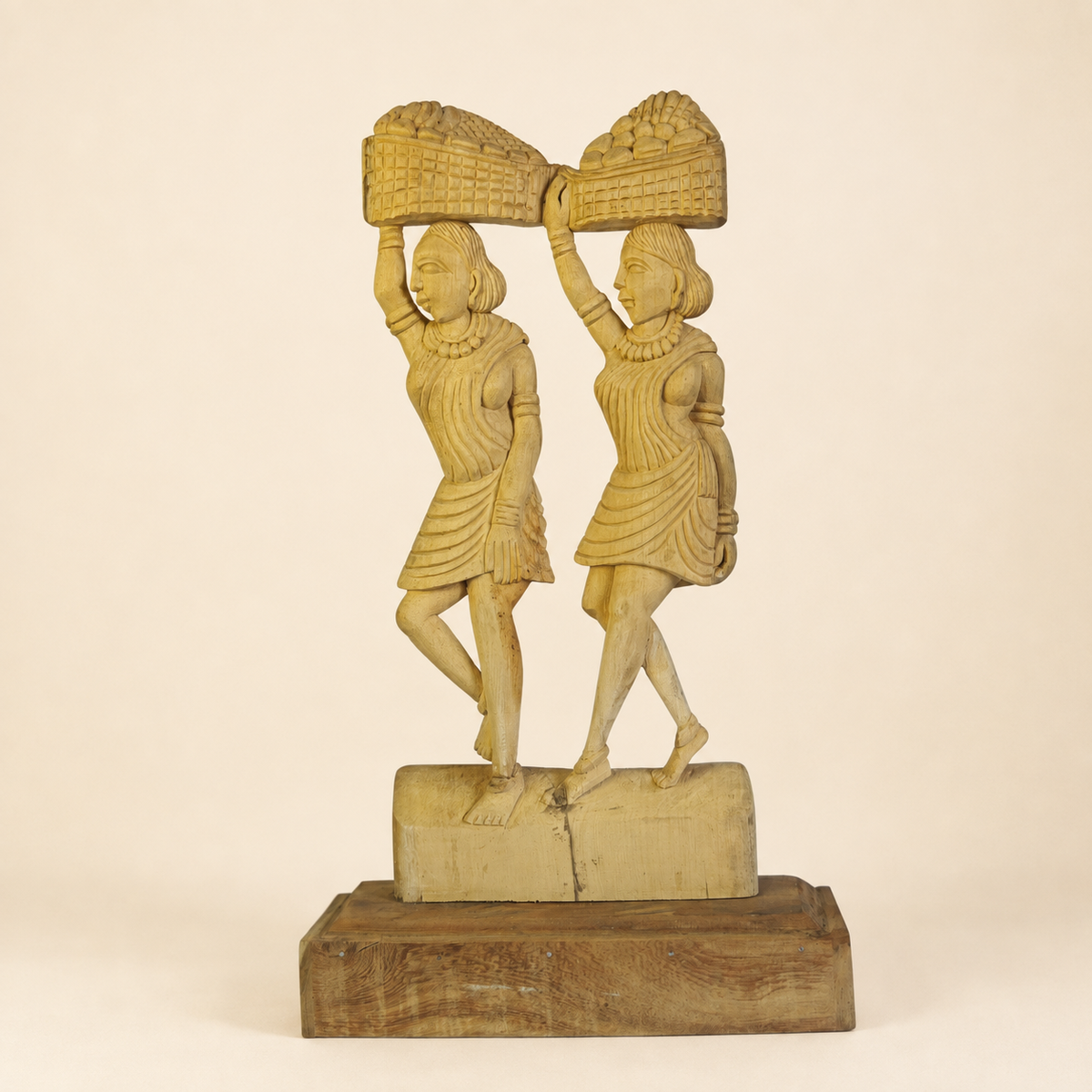 Bastar wood carving of two tribal women carrying connected baskets on a clean ivory background